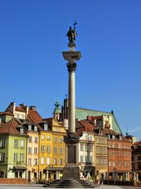 Statue in city against sky