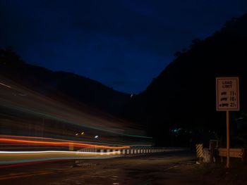 Light trails on road against sky at night