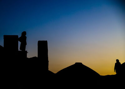 Silhouette people standing against clear sky during sunset