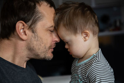 Side view of mid adult man looking at son with down syndrome