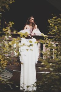 Low angle view of bride with wedding dress standing on balcony