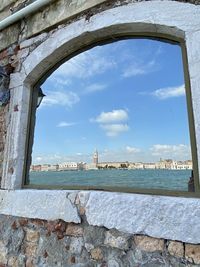 River by buildings against sky seen through window