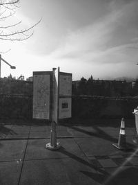 Road sign on footpath by street against sky