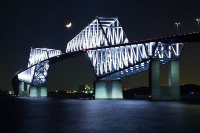 Illuminated suspension bridge over river at night