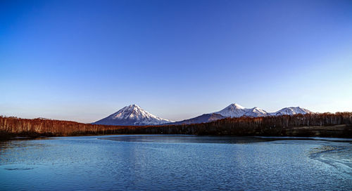 Scenic view of lake and snowcapped mountains against clear blue sky