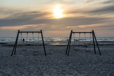 Lifeguard hut on beach against sky during sunset