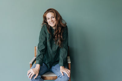 Portrait of young woman standing against wall