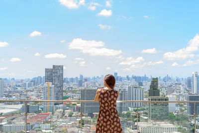Rear view of man looking at cityscape against sky