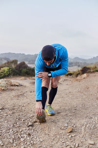 Man stretching leg on dirt road