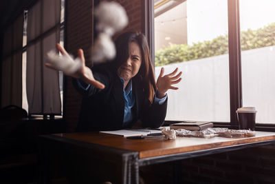 Midsection of woman using mobile phone at window