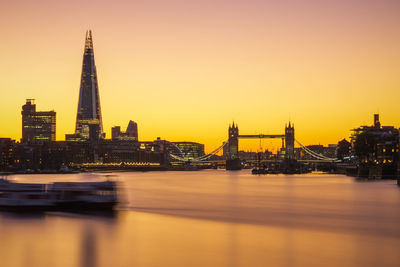 River in city against sky during sunset