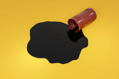 Low angle view of silhouette man holding bottle against yellow background