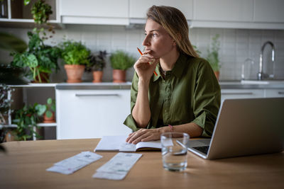 Female accountant freelancer working at home analysing company budget, counting income and expenses