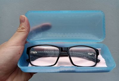 Close-up of cropped hand holding box with eyeglasses