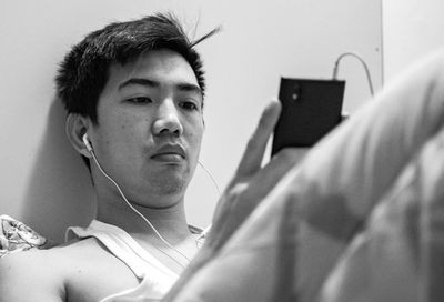 Close-up of man using mobile phone while sitting on bed at home