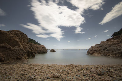 Long exposure picture of a rocky beach under a blue sky in costa brava