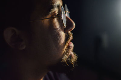 Close-up of man wearing eyeglasses looking away while at home