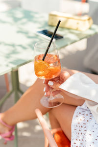 Female drinking iced aperol spritz cocktail in the city