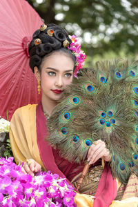 Woman in traditional clothes holding peacock feathers