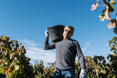 Full length of young man standing against blue sky