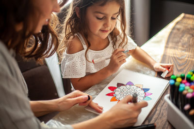 Mother and daughter while sitting on table