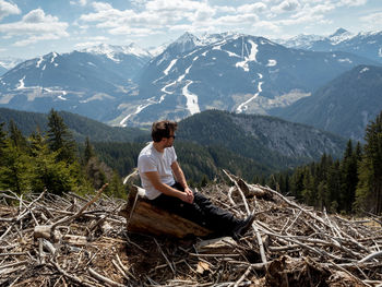 Man sitting on wood against mountains