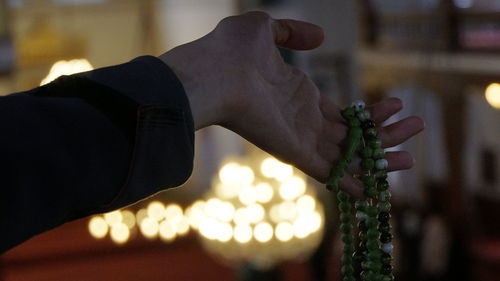 Close-up of human hand holding bead necklace at home