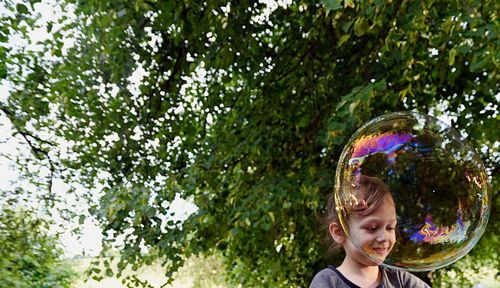 Girl seen through bubble against trees