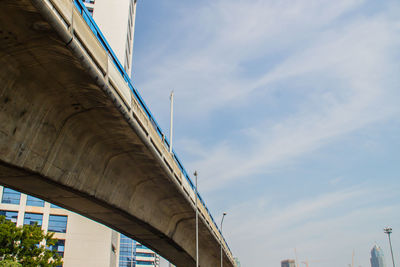 Low angle view of elevated road amidst buildings against sky