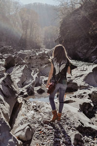 Rear view of woman standing on rock in forest