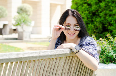 Portrait of young woman sitting on railing