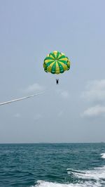 Person paragliding in sea against sky