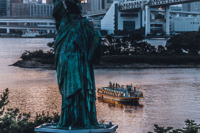 Statue in river with city in background