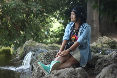 Side view of young woman standing on tree trunk