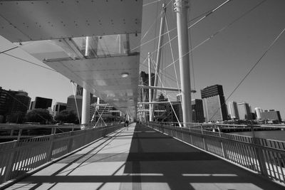 Footbridge over river against cityscape during sunny day