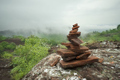 Stack of rocks in forest against sky