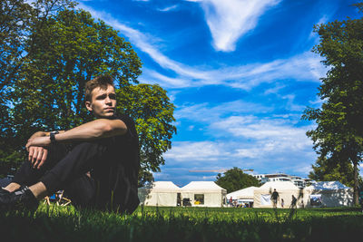 Young woman sitting on land against sky