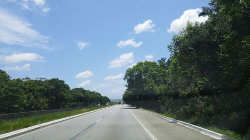 Road amidst trees against sky