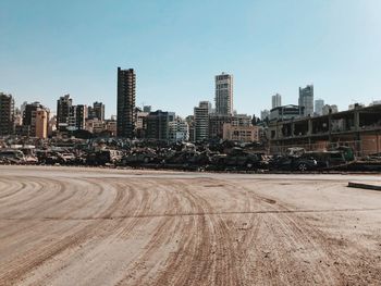 Road by buildings and stack of cars destroyed by the beirut explosion against sky in city