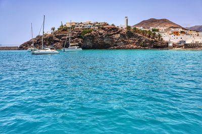 Swimming pool by sea against clear blue sky