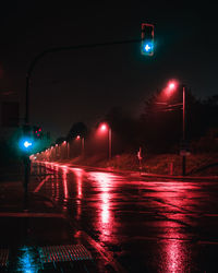 Illuminated road sign on wet street at night