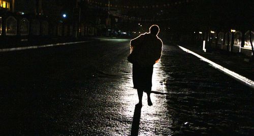 Full length of silhouette man walking on road at night