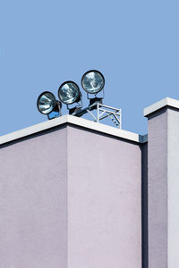 Low angle view of lighting equipment on wall against clear sky