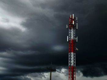Low angle view of communications tower against cloudy sky