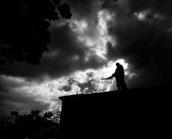 Low angle view of silhouette man standing against sky
