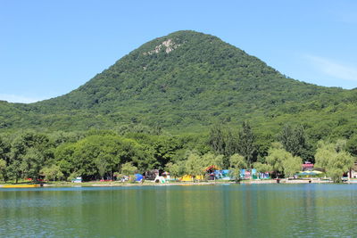 Group of people on mountain by lake against sky