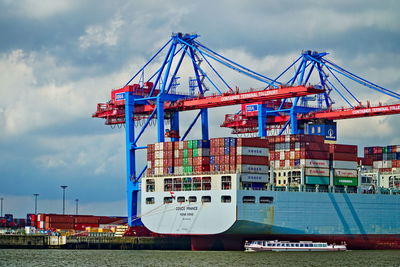 Cranes at commercial dock against sky