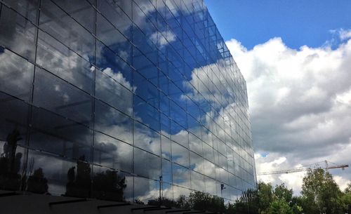 Low angle view of modern building against cloudy sky