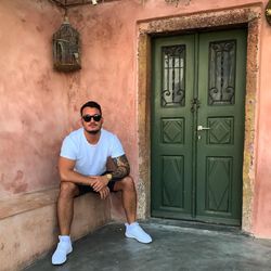 Full length portrait of young man sitting outside house