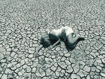 High angle view of woman lying down on cracked land